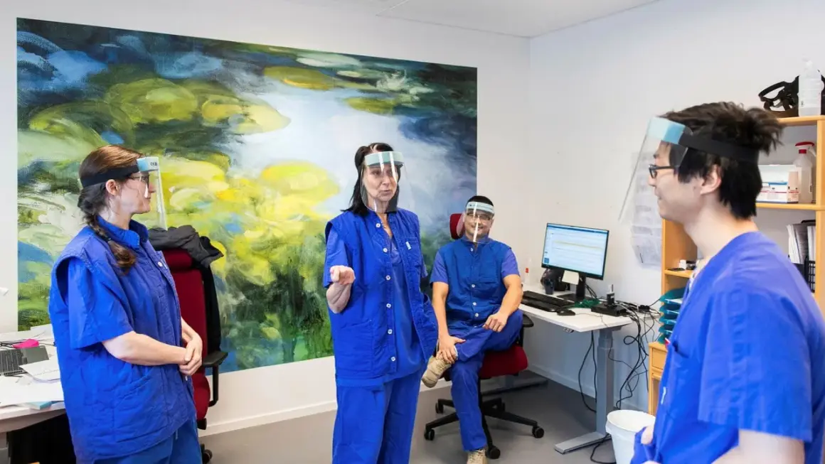 Personal med visir och blå kläder diskuterar gynekolog utbildning.