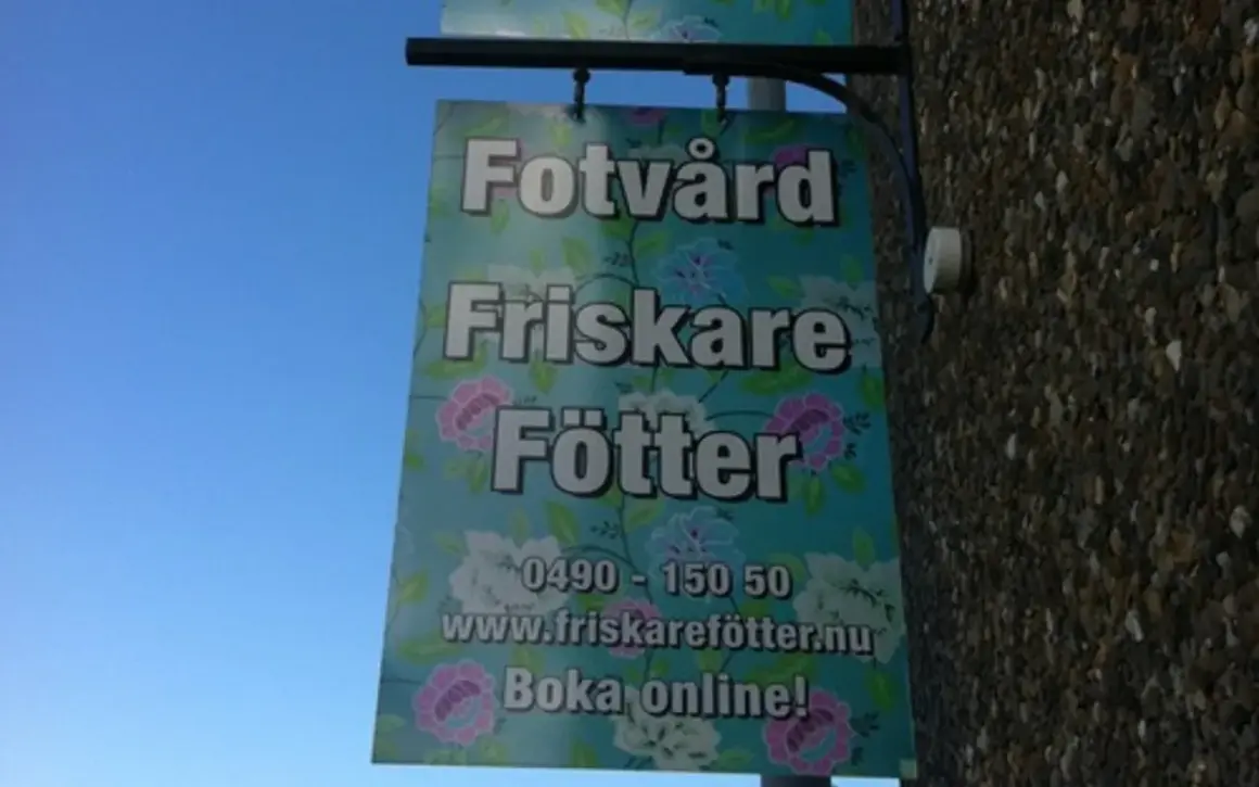 Skylt för "Fotvård Friskare Fötter" med blomstermönster. Erbjuder fotvård och fotvård utbildning. Boka online!