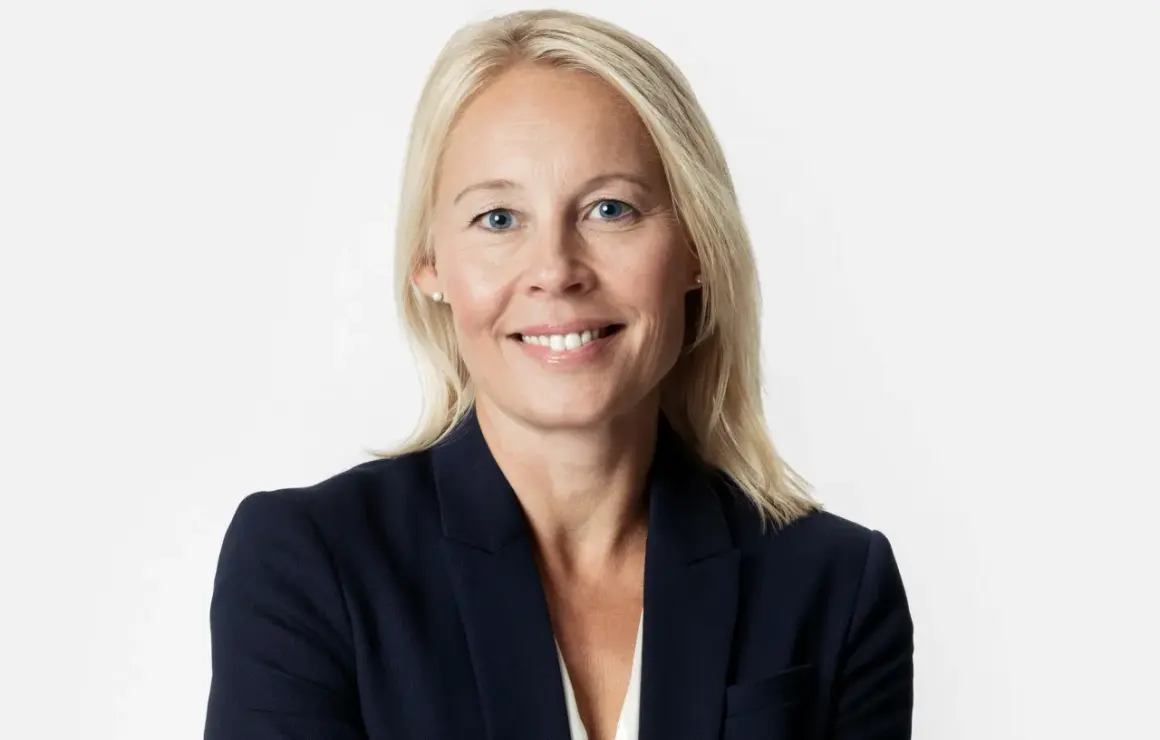 En kvinna med blont hår och blå ögon i mörk kavaj. Hon ler mot kameran, kanske efter att ha löst ett GDPR-incident.
