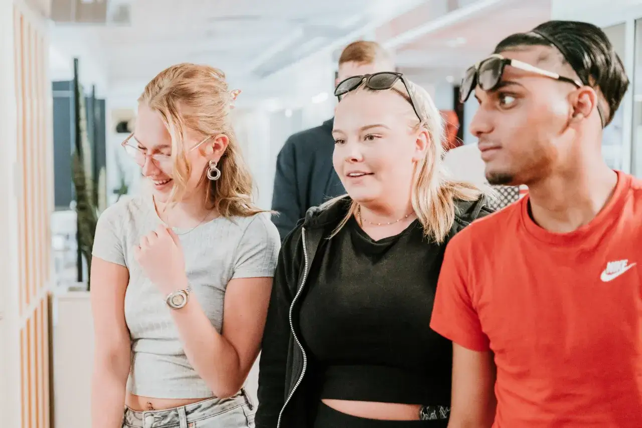 Tre unga v&auml;nner skrattar och pratar vid Morabergs studiecentrum.