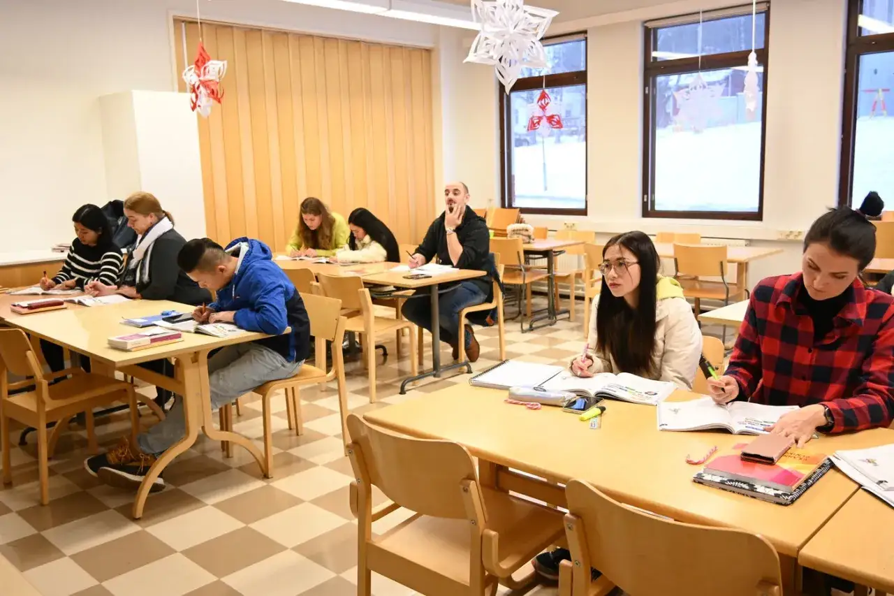 Elever deltar i kompetensutveckling och utbildning i ett klassrum. De sitter vid bord och skriver i böcker.