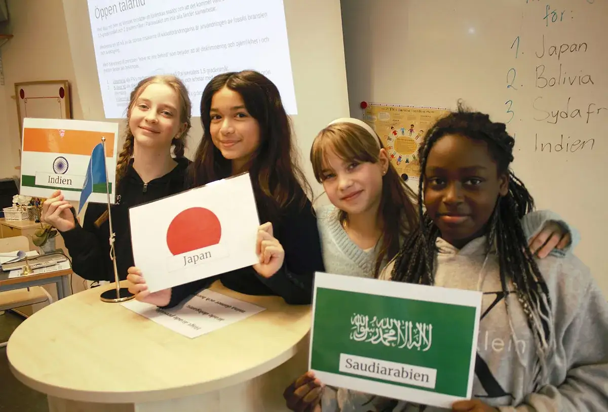 Fyra flickor i en skola h&aring;ller upp flaggor fr&aring;n Indien, Japan, Saudiarabien och en annan ok&auml;nd flagga.