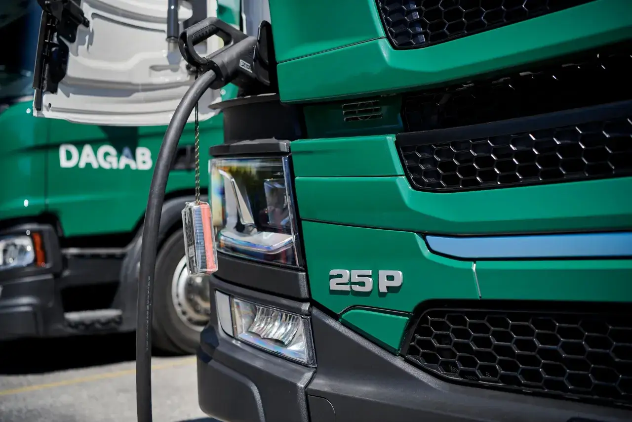 Gr&ouml;n lastbil laddas, redo f&ouml;r effektiv logistik. En konsult ser till att allt flyter smidigt.