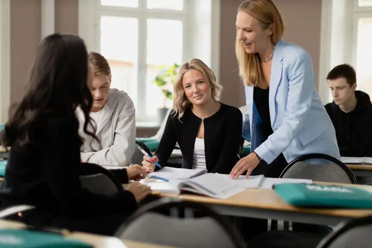 Elever p&aring; ekonomiprogrammet gymnasiet arbetar med uppgifter medan l&auml;raren ger instruktioner.