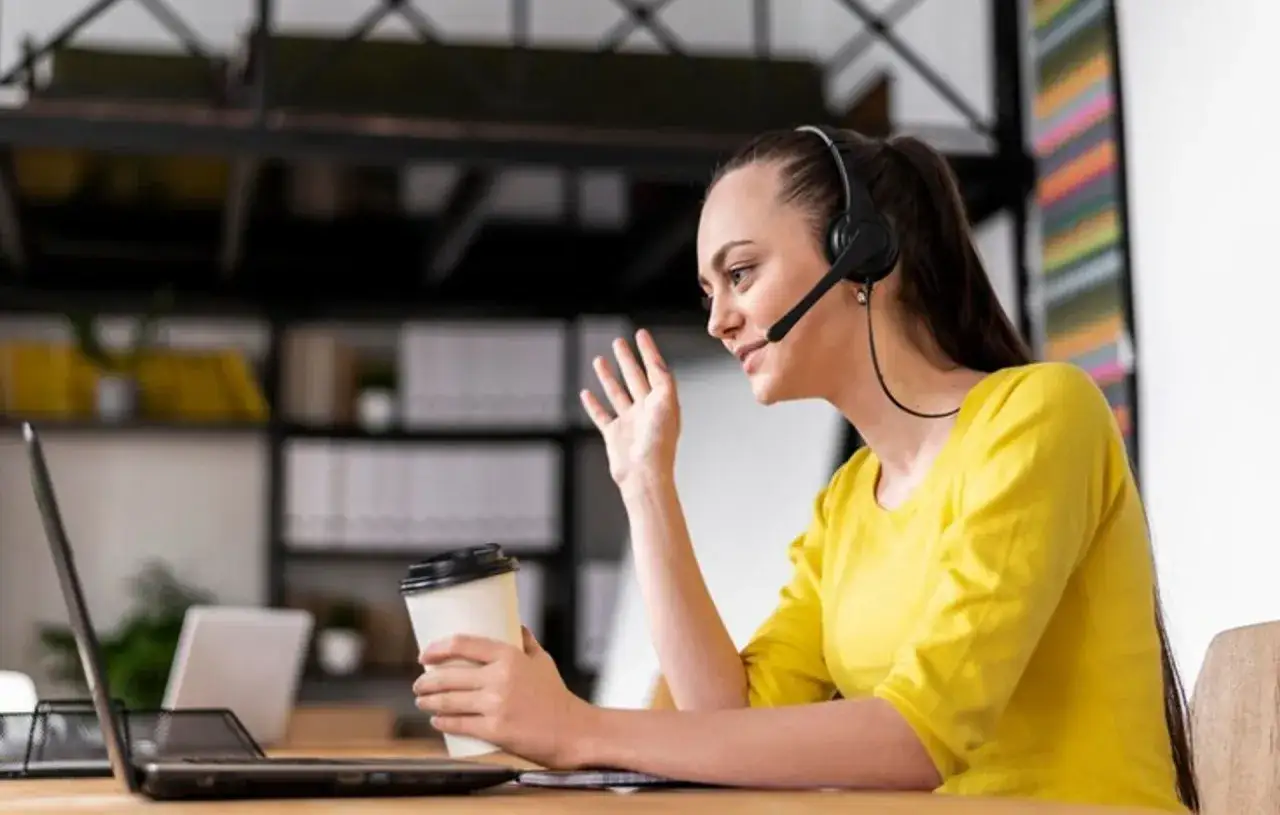 Kvinna med headset och kaffemugg deltar i virtuell assistent utbildning via sin laptop.