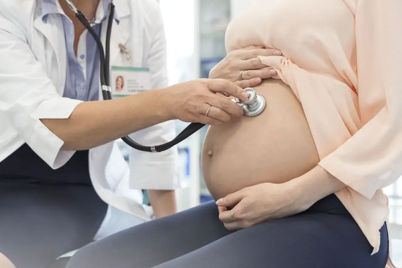 L&auml;kare lyssnar p&aring; ett barns hj&auml;rtslag p&aring; en gravid mage. En del av gynekolog utbildning.