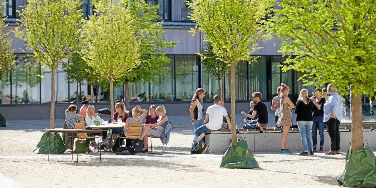 Studenter samlas utomhus vid en modern byggnad, kanske under en paus fr&aring;n sin agronom utbildning.