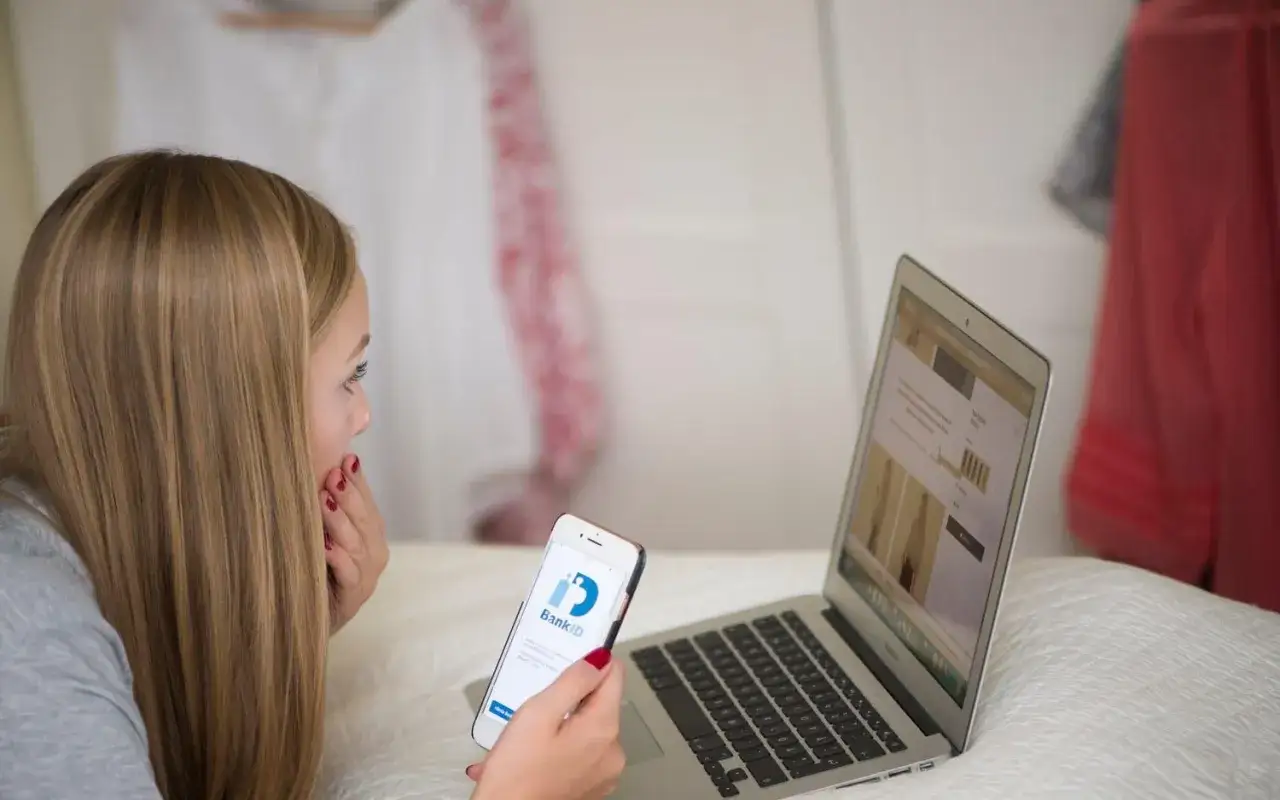 Ung kvinna anv&auml;nder BankID p&aring; mobilen f&ouml;r att handla online, medveten om sina r&auml;ttigheter enligt lagen om distansavtal.