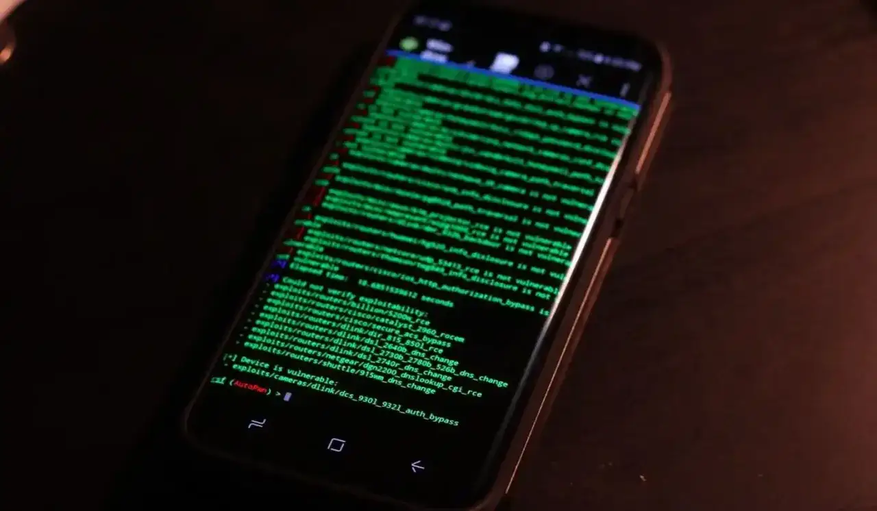 En mobiltelefon visar gr&ouml;n text med kod som en forensiker skulle analysera. Den listar potentiella s&aring;rbarheter i n&auml;tverksenheter.