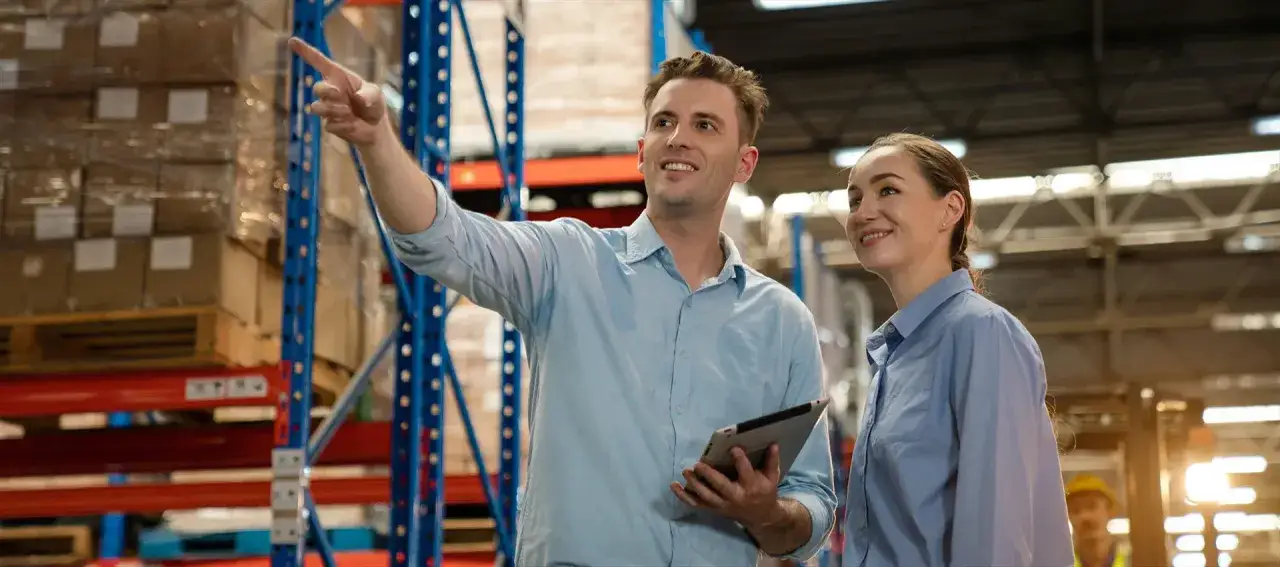 Man pekar och kvinna lyssnar i lager. De verkar l&auml;ra sig om hur man plugga logistik.