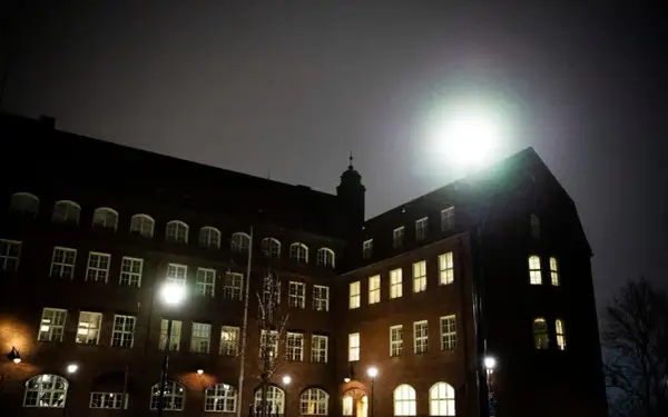 Mörkt tegelhus med många fönster lyser upp natten. Hvitfeldtska gymnasiet ser imponerande ut i det svaga ljuset.