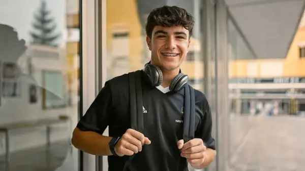 Ung kille med hörlurar och ryggsäck, redo för en **rig fotboll**-träning.