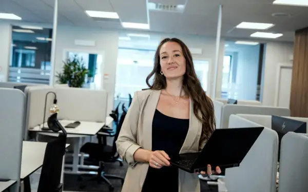 Kvinna med laptop i modernt kontorslandskap, redo att jobba med reklam.