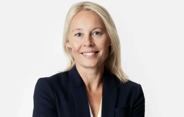 En kvinna med blont hår och blå ögon i mörk kavaj. Hon ler mot kameran, kanske efter att ha löst ett GDPR-incident.